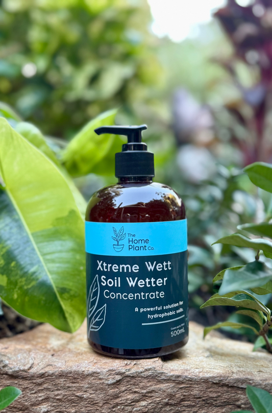 Bottle of Xtreme Wett Soil Wetter Concentrate on a stone surface with green foliage in the background